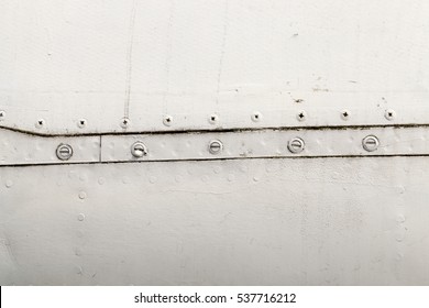   metal surface of old unused airplane gray. In paint, some visible damage, as well as metal rivets and bolts connecting the sheets of material. Small depth of field.