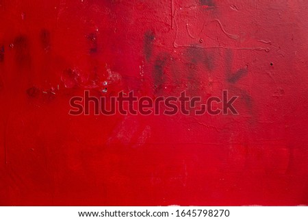 metal surface painted with red paint with streaks and barely distinguishable inscription work. Red grunge background