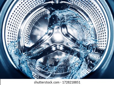 Metal surface of the washing machine drum. Water splashes in washing machine drum, close up