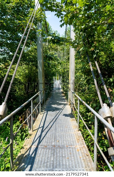 Metal suspension rope bridge in nature. Scenic\
view. Steel footbridge