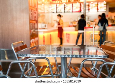 Metalltisch und -stühle im chinesischen Café für Fastfood in Food Court mit unscharfem Counter-Menü und Tablett, Fokus auf Möbel - Hintergrund für öffentliche Verpflegung
