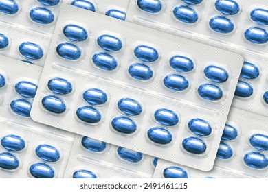 Metal tablet blister. Blue pills medicine. Silver shiny blister with drugs. Capsules in blister pack closeup. Medicament texture. Pile of aluminum pills blisters. Drug addiction background.