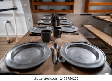 metal tableware for sailors and passengers on the table the lower deck on an old sailing ship