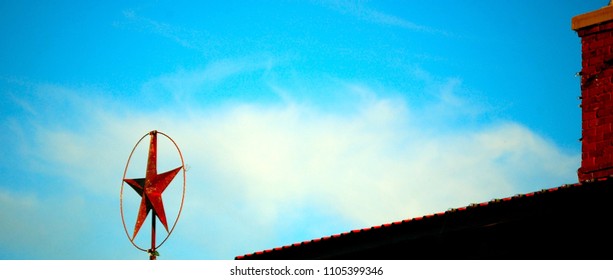 Metal Texas Star On Building Roofline Against Blue Sky And White Clouds