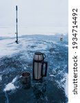 Metal thermos with a hot drink on the background of pure ice at Lake Baikal. Thermos for tea on a fishing trip.