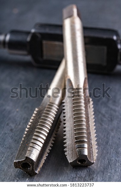 Metal thread cutting tools. Tool steel\
accessories for locksmiths. Light\
background.