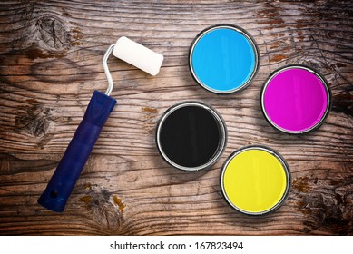 Metal Tin Cans With Four Process CMYK Colors With Paint Roller. Printing Industry Conceptual Background, Top View