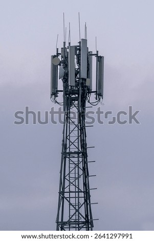 Metal tower with multiple cellular repeaters against cloudy sky. Repeater tower against cloudy sky.