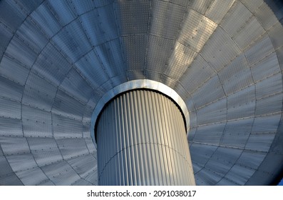 metal tower of reservoir clad with sheet metal aluminum cladding. rivets and corrugated sheets resemble a spaceship, or an alien UFO civilization. silver metallic shiny column and conical water tank