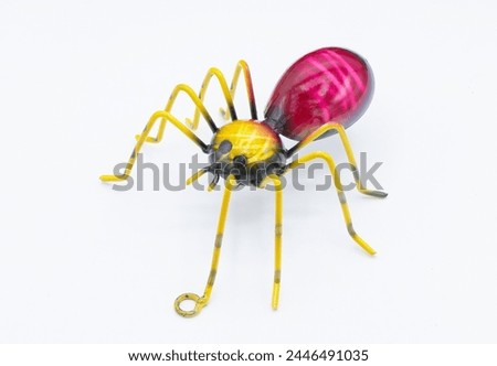 Metal wall art of a spider arachnid,  red, purple yellow color with 8 legs and large abdomen isolated on white background. made for hanging up indoor or outdoor