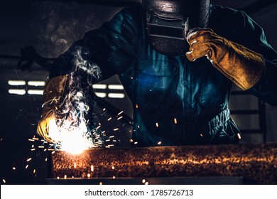 Metal welder working with arc welding machine to weld steel at factory while wearing safety equipment. Metalwork manufacturing and construction maintenance service by manual skill labor concept.