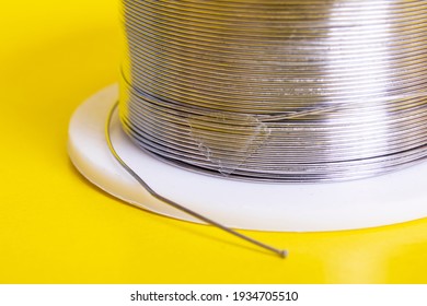 Metal Wire Spool On A Yellow Background Close Up