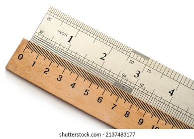Metal and wooden rulers on a white background. The units of measurement are centimeters and inches.