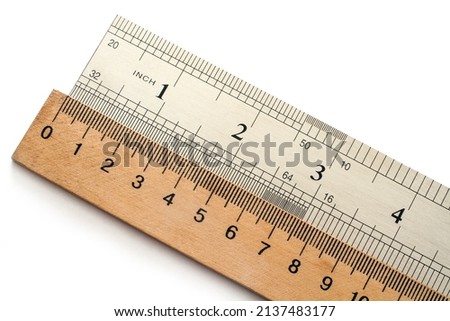 Metal and wooden rulers on a white background. The units of measurement are centimeters and inches.