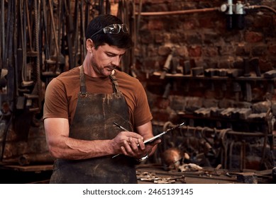 Metal worker, clipboard and writing notes in workshop for manufacturing, welding and blacksmith. Tradesman, tools and equipment in factory with apron for artisan, industrial steel and manual labor - Powered by Shutterstock