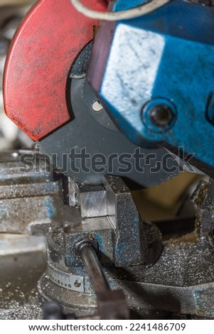 Metal worker cuts piece of metal with a metal cutoff saw - close-up cutoff cutter