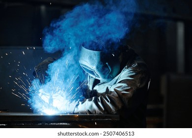 Metal worker performing welding with sparks flying in workshop, wearing protective gear and facemask for safety, focused on task in metalworking environment - Powered by Shutterstock