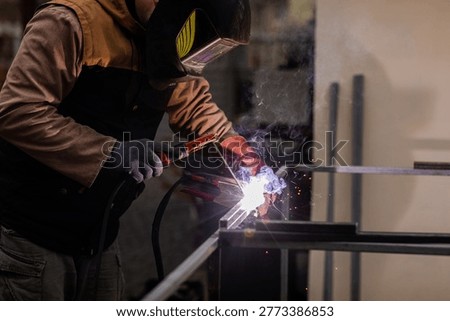 Metal worker performs welding at workshop during evening hours in industrial setting