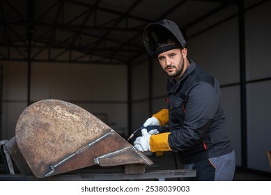 Metal worker wearing protective gear using welding torch for welding metal part in workshop - Powered by Shutterstock