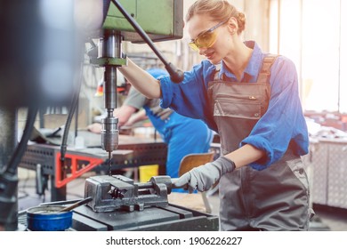 Metal worker woman operating drilling machine concentrating on her job - Powered by Shutterstock