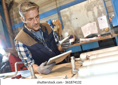 Metal Worker In Workshop Using Digital Tablet