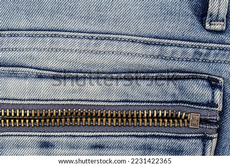 Metal zipper on light blue jeans pocket.