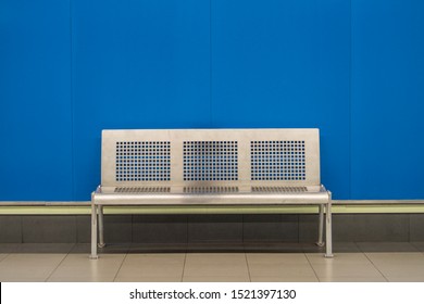 Metallic bank in a Madrid subway station with a blue wall background