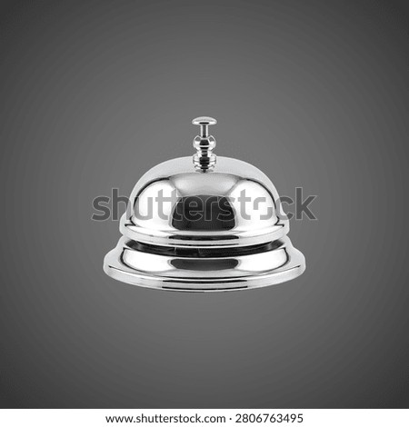 A metallic call bell with a black button, placed on a smooth reflective surface against a dark backdrop.