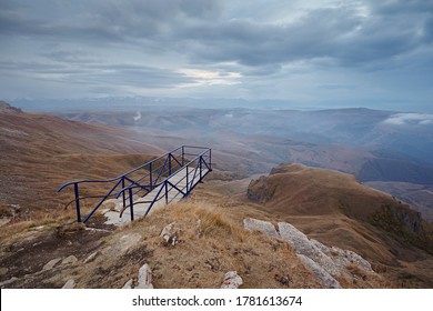 Metallic dangerous bridge over a precipice in the mountains against the background of clouds and scenery in the evening.
