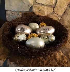 Metallic Eggs In A Giant Nest. Huge Gold And Silver Eggs In A Pine Needle Nest On A Stone Fireplace Hearth.