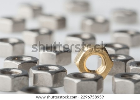 Metallic hex nuts layed out on a table, industrial background. All steel and one brass nut. Selective DOF