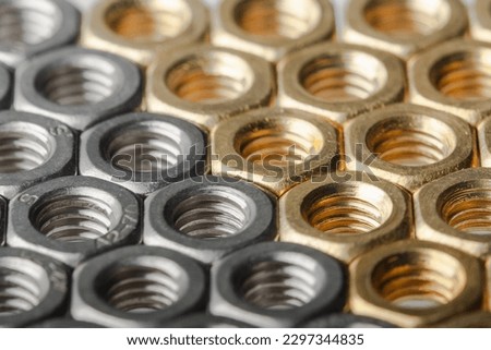 Metallic hex nuts layed out in a hexagonal pattern, industrial background. Mix of steel and brass nuts