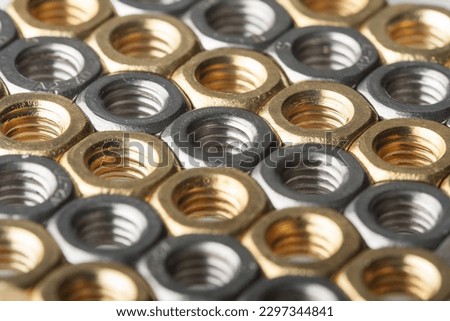 Metallic hex nuts layed out in a hexagonal pattern, industrial background. Mix of steel and brass nuts