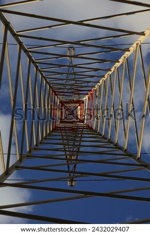 Metallic High Voltage Electricity Grid Pylon seen from below with blue sky