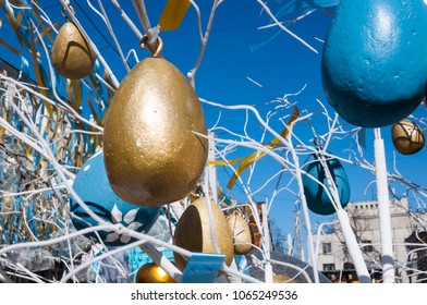 Metallic multi-colored eggs hanging on a spring tree against the bright blue sky - Powered by Shutterstock