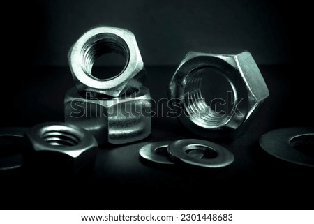 Metallic nuts and washers. Low-key concept picture taken in studio with soft-box and dark background representing some mechanical components.