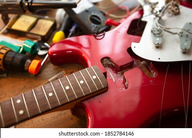 Metallic red electric guitar on guitar repair workbench or a desk,  in repair or maintenance. Pickguard detached. Double cutaway solid body guitar. Shallow depth of field. - Powered by Shutterstock