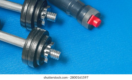 Metallic rods feature threaded ends. Black cylindrical parts surround the threads. One component has a red end. Blue fabric background contrasts these industrial items