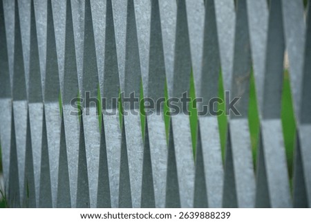 Metallic rods form a rhythmic pattern against a green background. Geometric shapes, sharp textures, and repeating lines create a modern abstract industrial texture, ideal for design.