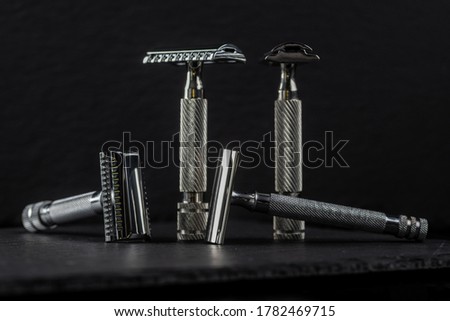 Metallic safety razors on dark background, barber shop concept