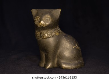 Metallic statuette of a cat isolated in dark background 