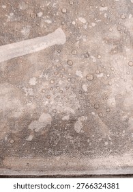 Metallic surface with circular formations resembling bubbles, corrosion, or chemical reaction residues.