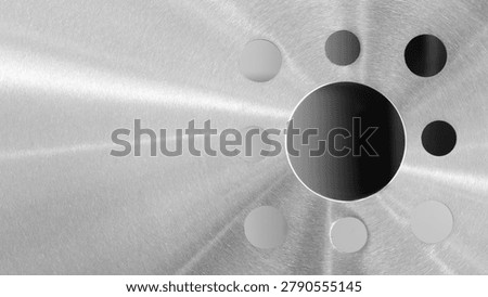 Metallic surface shows brushed texture with subtle highlights, Light rays emanate from a central black circle
