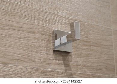 metallic wall hook mounted on a textured wooden surface hook is square-shaped with a modern, minimalist design, featuring a shiny, reflective finish. This type of hook is typically used for hanging - Powered by Shutterstock