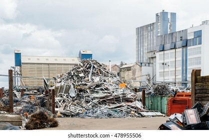 Metallic waste solution dump pile in the yard of a factory with big furnace and processing unit in the background  - Shutterstock ID 478955506