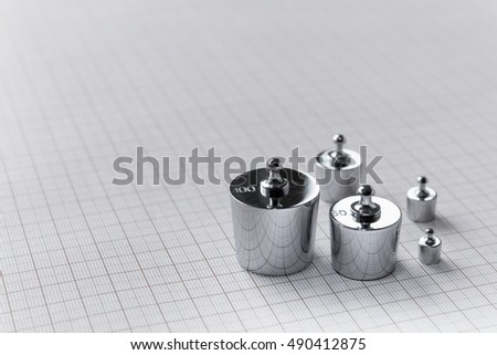 Metallic weights on background of millimeter paper. Metrology and measurements tools.