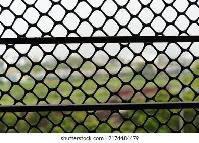 Metallic window frame fence through which everything is visible on the other side
