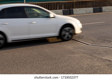 Metallic Zigzag Edge Of Drainage Channel On Asphalt. A Blurry Car Over A Movable Joint On The Roadway Of The Bridge For Simulate Fast Movement.