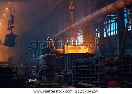 Metallurgy plant interior. Foundry worker on big mold for iron cast. Heavy industry. Steel factory