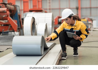 Metalwork manufacturing, warehouse of raw materials. Female factory worker inspecting quality rolls of metal sheet in factory during manufacturing process, wearing safety uniform, use digital tablet - Shutterstock ID 2282229847